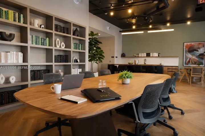 Built-in floor-to-ceiling shelving, herringbone wood-finish flooring, exposed ceiling piping, and a custom bar area with a built-in sink