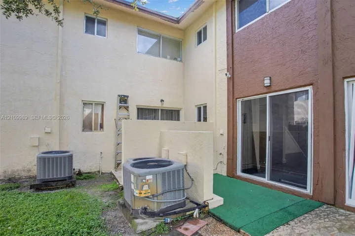 Stucco exterior featuring dual-tone paint, a sliding glass door, and dedicated outdoor utility space