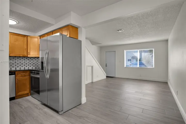 Kitchen featuring wood cabinetry, stainless steel appliances, and a tile backsplash, finished with wood-finish flooring