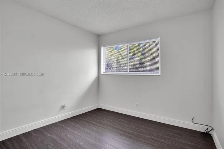 Interior room featuring wood-finish flooring, a horizontal sliding window, and textured ceiling finish