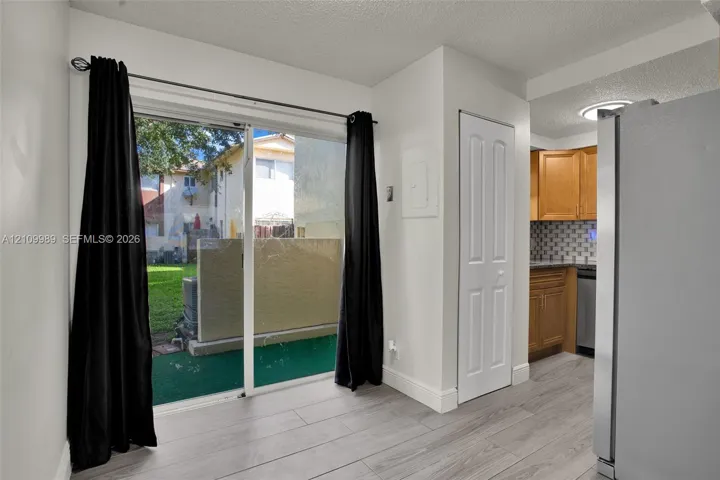 Sliding glass door, wood-finish flooring, built-in cabinetry, tiled backsplash, and stainless steel kitchen appliances