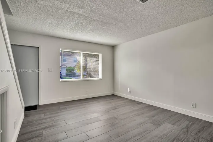 Neutral interior space featuring wood-finish tile flooring, neutral wall paint, and a rectangular window