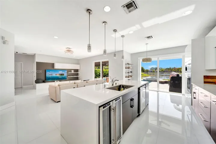 Kitchen featuring a waterfall-edge stone countertop, custom cabinetry, built-in dual wine refrigeration, recessed ceiling lighting, and large sliding glass doors