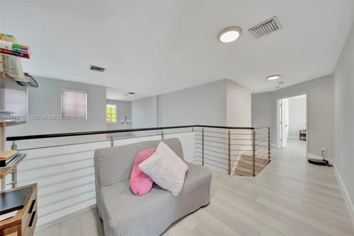 Open area featuring wood-finish flooring, metal cable railing, and recessed ceiling lighting