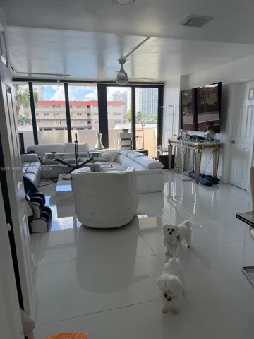 Open-concept interior featuring large-format polished tile flooring, expansive floor-to-ceiling windows, and a central ceiling fan