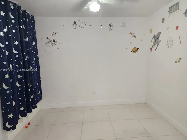 Interior room featuring large-format ceramic tile flooring, neutral white walls, and a ceiling-mounted light fixture