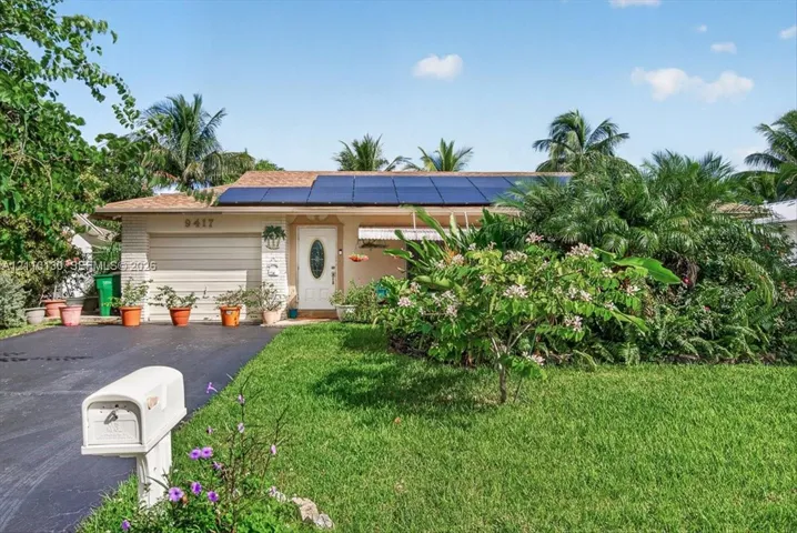 Single-story residence featuring a roof-mounted solar panel system, brick veneer exterior, attached one-car garage, and established landscaping
