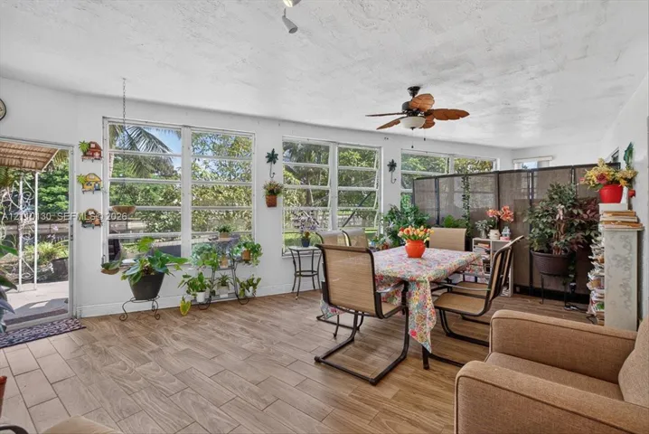 Sunroom featuring wood-finish tile flooring, a ceiling fan, and extensive windows with integrated crank-style hardware