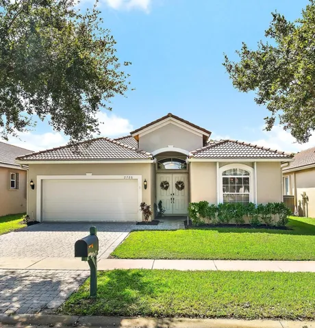 Stucco exterior featuring a tiled roof, arched entryway, double-door entrance, and a paved driveway