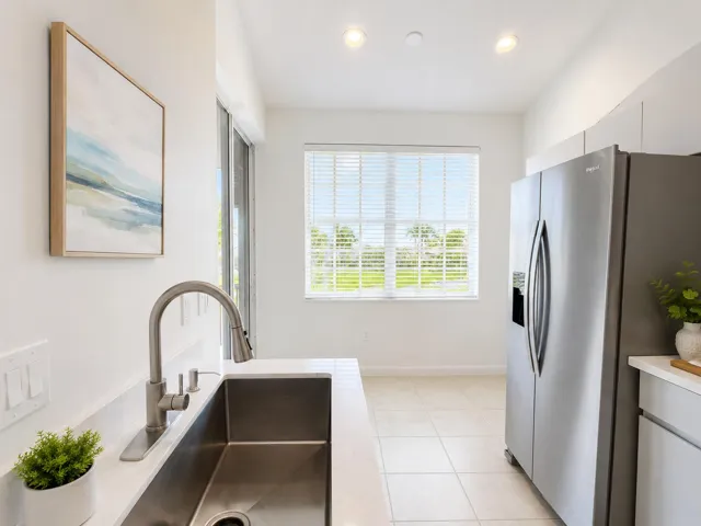 Stainless steel refrigerator, undermount rectangular kitchen sink with a high-arc pull-down faucet, quartz countertops, tile flooring, and recessed ceiling lighting