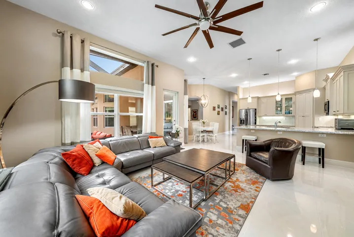 Open-concept living space featuring high ceilings, recessed lighting, expansive picture windows, tile flooring, and kitchen cabinetry with integrated peninsula seating