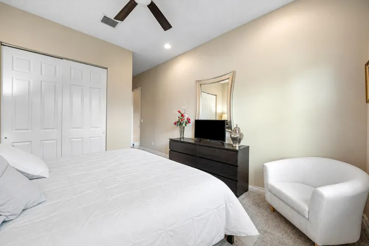 Neutral-toned interior featuring carpeting, a ceiling fan, and sliding closet doors