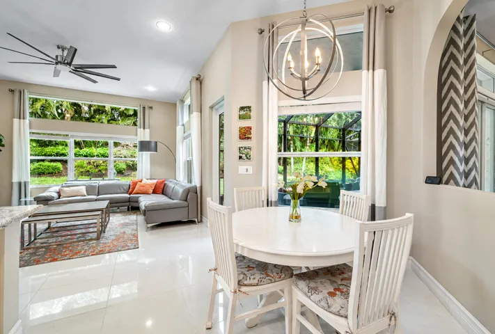 Open-concept area featuring high ceilings, large-format tile flooring, a multi-light spherical chandelier, and expansive windows