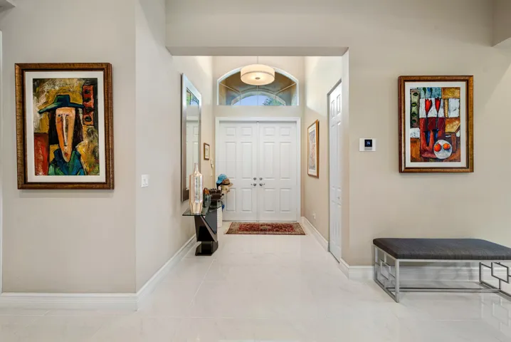Foyer featuring double-door entry, arched transom window, pendant lighting, and polished stone-finish flooring