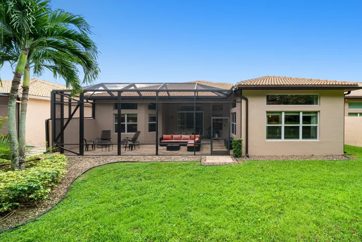 Exterior featuring a stucco facade, a screened-in lanai with paver flooring, a tile roof, and a landscaped lawn