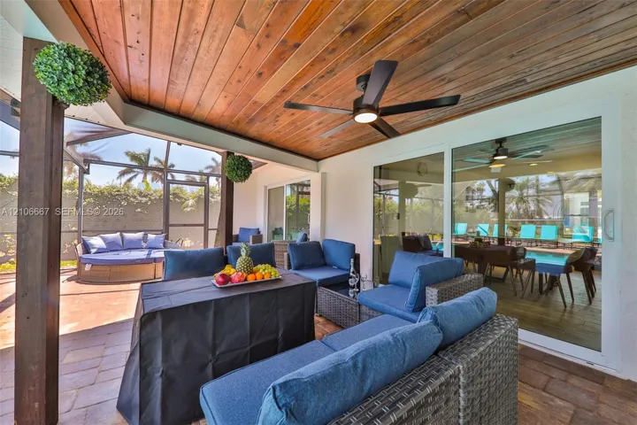 Covered patio featuring a wood-plank ceiling, ceiling fan, paver flooring, and a screened-in enclosure