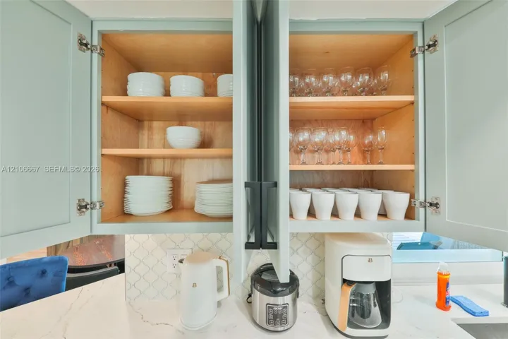 Shaker-style cabinetry with light-toned finish, matte black hardware, and an intricate arabesque tile backsplash