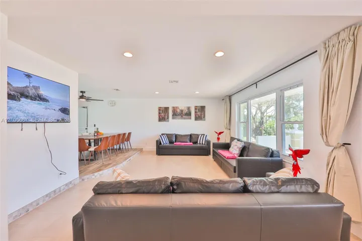 Open-concept interior featuring recessed lighting, light-toned flooring, multi-pane windows, and a raised platform area