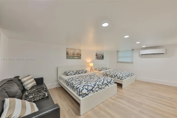 Wood-finish flooring, recessed lighting, and wall-mounted air conditioning unit