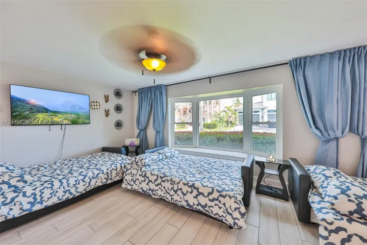Bay window, wood-finish tile flooring, and ceiling fan with integrated lighting