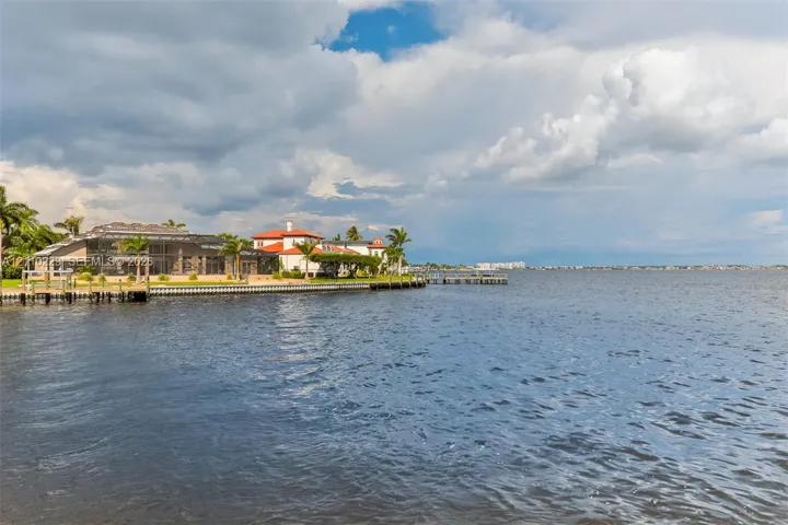 Waterfront property featuring a private dock, bulkhead, and multi-story residence with a tile roof