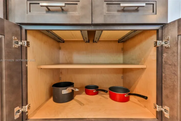Dark-stained cabinetry featuring shaker-style doors, horizontal brushed-nickel hardware, full-extension interior pull-out shelving, and adjustable shelving