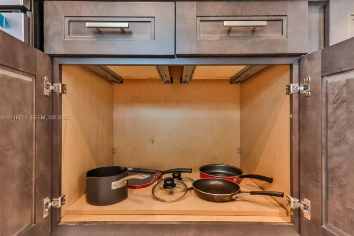 Dark-toned cabinetry featuring shaker-style doors, horizontal brushed metal hardware, and an interior slide-out wooden shelf