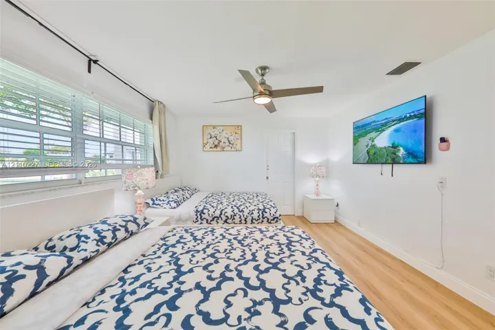 Interior space featuring wood-finish flooring, a multi-pane horizontal window, and a brushed nickel ceiling fan with integrated lighting