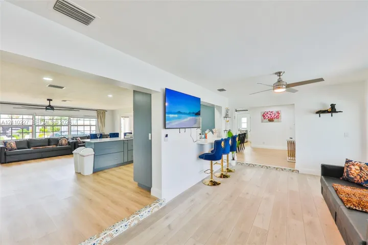 Open-concept interior featuring light wood-finish flooring, recessed lighting, ceiling fans, and a built-in counter