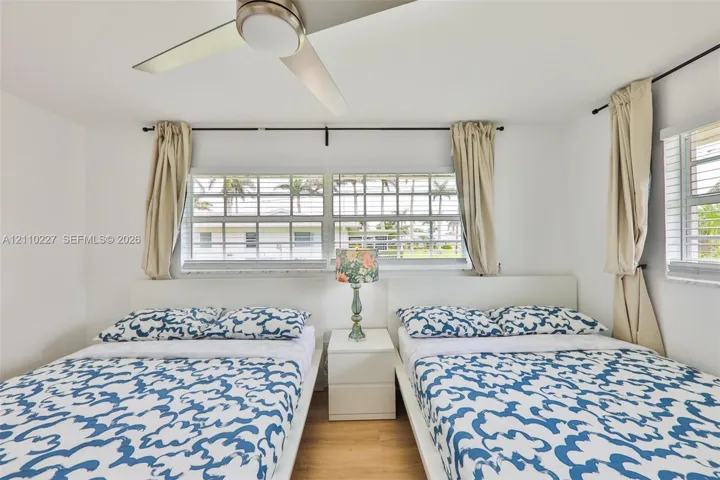 Room featuring wood-finish flooring, a contemporary ceiling fan with integrated lighting, and multiple horizontal sliding windows with metal rod hardware