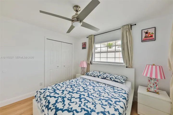 Wood-finish flooring, brushed nickel ceiling fan with integrated lighting, dual-panel closet doors, and multi-pane horizontal window