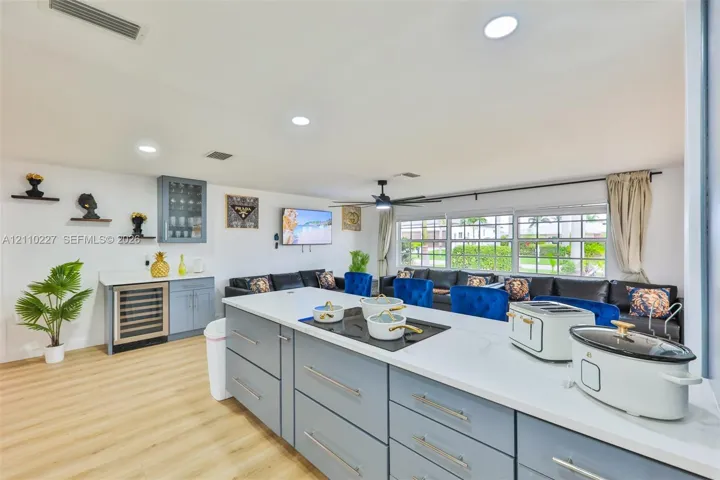 Kitchen featuring light blue cabinetry, stone-finish countertops, built-in under-counter beverage refrigerator, recessed lighting, and wood-finish flooring