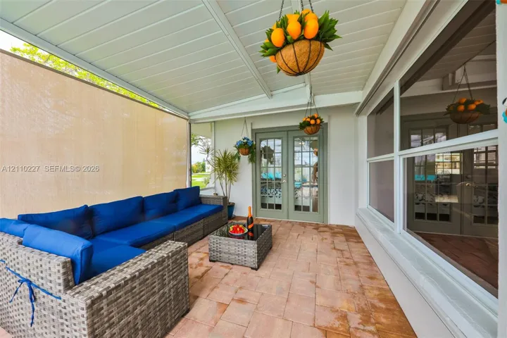 Covered patio featuring a paved floor, beadboard ceiling, privacy screening, and French doors