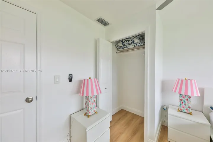 Interior space featuring wood-finish flooring, a reach-in closet with integrated shelving and hanging rod, and a multi-panel interior door