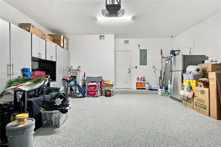 Garage featuring an epoxy floor finish, built-in white cabinetry with bar pulls, and a dedicated exterior-access door