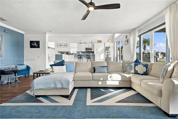 Open-concept floor plan featuring wood-finish flooring, a sleek ceiling fan, and expansive glass doors