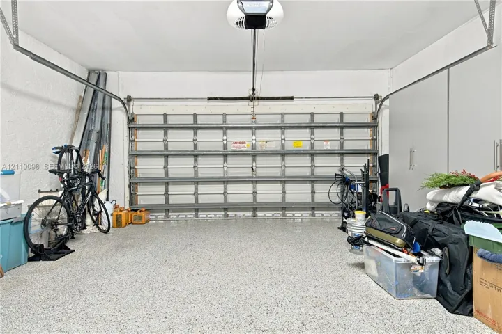 Two-car garage featuring a sectional metal door, epoxy-coated concrete flooring, and ceiling-mounted automatic door opener