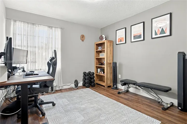 Neutral-toned interior room featuring wood-finish flooring and a single-pane window with adjustable curtains