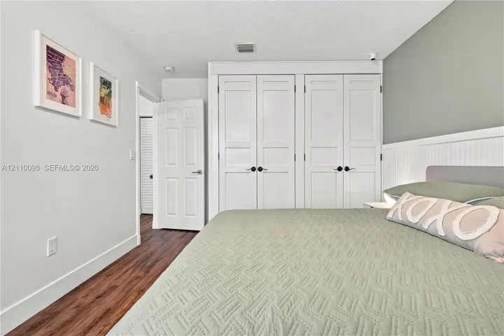 Wood-finish flooring, built-in floor-to-ceiling cabinetry with shaker-style doors, and decorative beadboard wainscoting