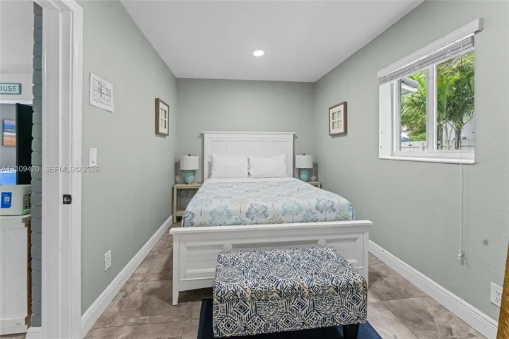 Neutral-toned interior space featuring light-colored wall finish, ceramic tile flooring, and a single-pane window