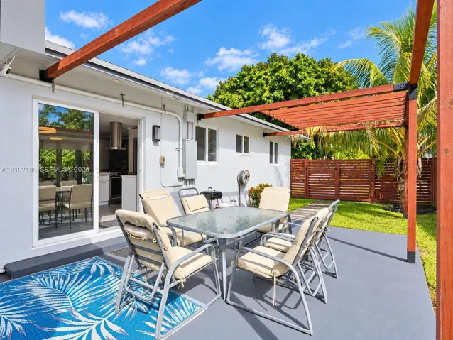 Covered patio featuring a stained wood pergola, concrete flooring, and horizontal wood privacy fencing