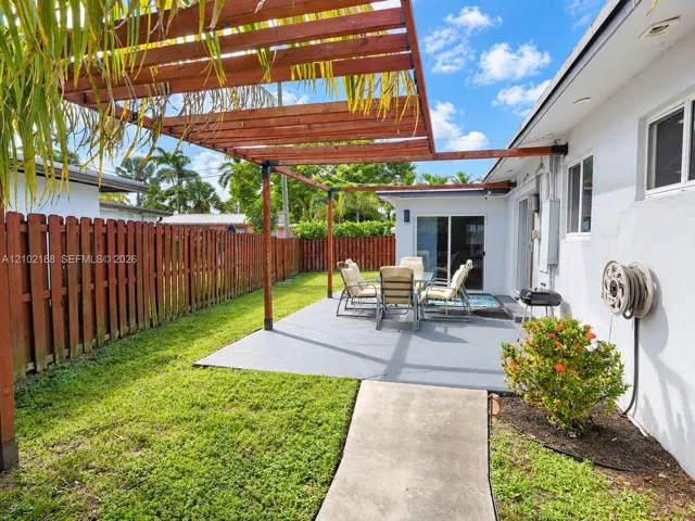 Backyard featuring a custom wood pergola, concrete patio, privacy fencing, and a manicured lawn