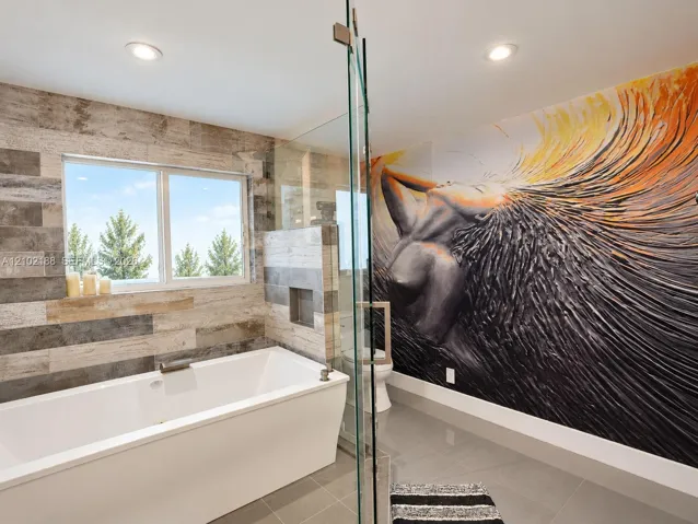 Freestanding soaking tub, wood-finish wall tile, recessed shower niche, glass shower enclosure, and recessed lighting