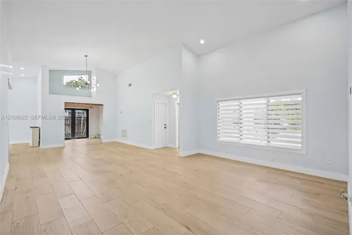 Vaulted ceilings, wood-finish flooring, recessed lighting, double French doors, and horizontal slat window treatments