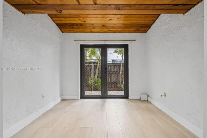 Wood-plank ceiling, textured wall finish, wood-finish flooring, and dark-framed French doors