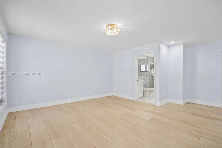 Spacious room featuring wood-finish flooring, neutral wall paint, and a central flush-mount light fixture