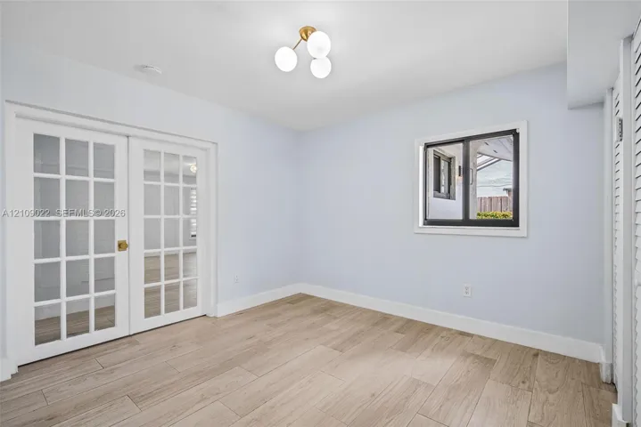 Wood-finish tile flooring, multi-pane French doors, and a modern three-globe flush-mount light fixture