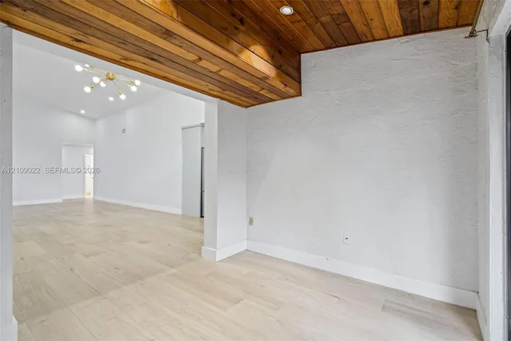 Textured walls, wood-finish flooring, recessed ceiling lighting, and wooden plank ceiling detailing