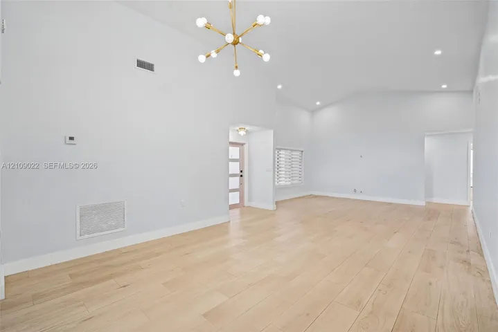 High-ceiling interior featuring wood-finish flooring, a contemporary multi-arm sputnik chandelier, recessed lighting, and a multi-panel exterior entry door with glass inserts