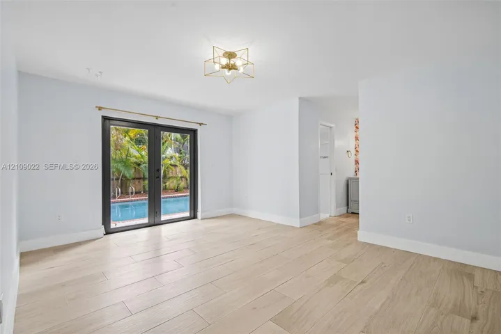 Interior space featuring wood-finish tile flooring, recessed lighting, geometric metal flush-mount fixture, and double glass-pane doors